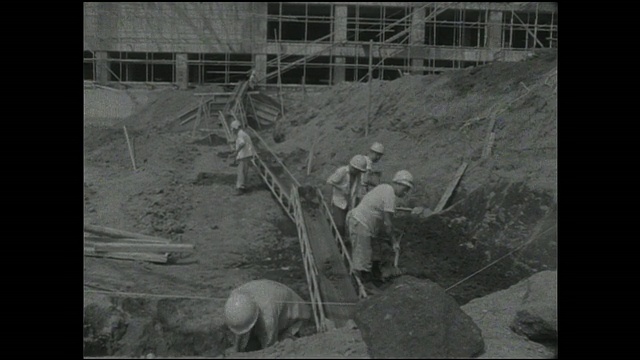 在东京塔建筑项目的基础上，建筑工人正在用传送带铲土。视频素材