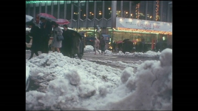 银座4丁字路口积雪成堆，行人撑着雨伞走过。视频素材