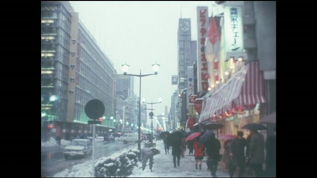 一名男子铲掉人行道上的雪，行人拿着雨伞走过。视频素材