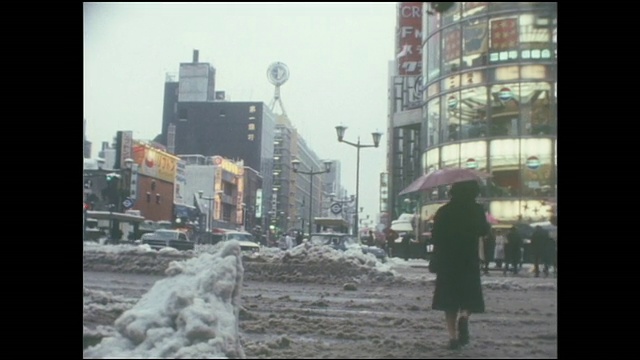 银座4丁目十字路口，行人撑着雨伞走过成堆的积雪。视频素材