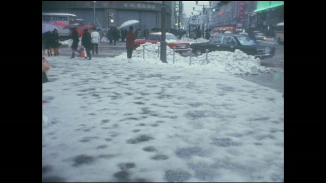 行人在银座4丁字路口附近的积雪人行道上小心行走。视频素材