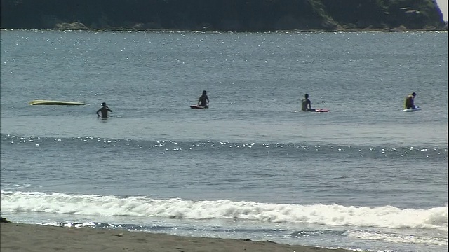 男男女女喜欢在湘南海滩附近冲浪和皮划艇。视频素材