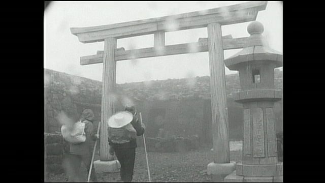 登山者在雨中穿过富士山峰顶的鸟居门。视频素材