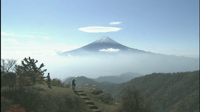 游客们看着悬在富士山上空的云帽。视频素材