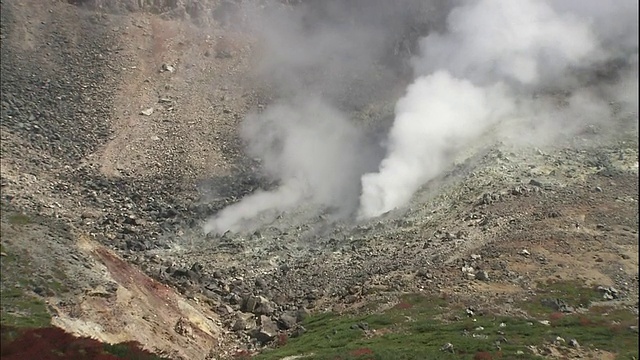 在覆盖山坡的秋叶附近，一缕烟雾从Nasudake火山升起。视频素材