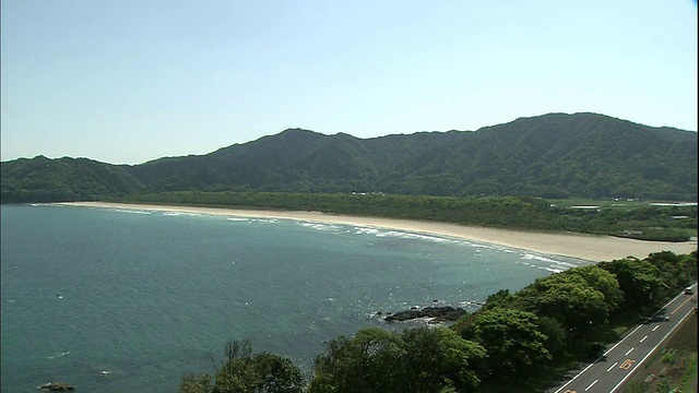 在日本，海浪冲刷着山和绿树成荫的海滩。视频素材