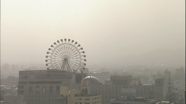 在日本松山，亚洲的灰尘掩盖了高层建筑和摩天轮。视频素材