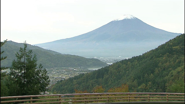 日本富士山上覆盖着积雪，这座山耸立在一个小山村的上空。视频素材