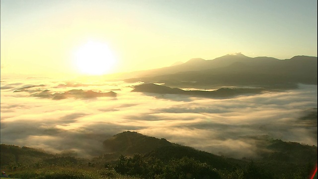 炽热的太阳将金色的光芒投射在环绕着木岛山脉的云海上。视频素材