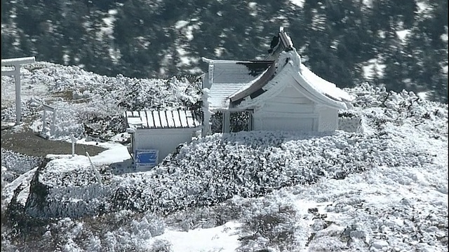 白雪覆盖了神社和鸟居门在一个山顶上的藏山山脉，日本。视频素材