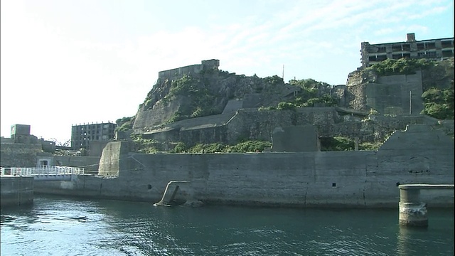 一堵墙保护着日本长崎荒废的端岛的海岸线。视频素材