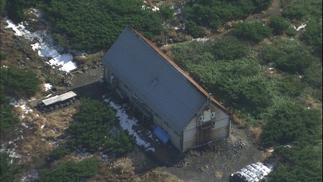 日本北海道Yotei山上，灌木和树木环绕着一个孤零零的小屋。视频素材