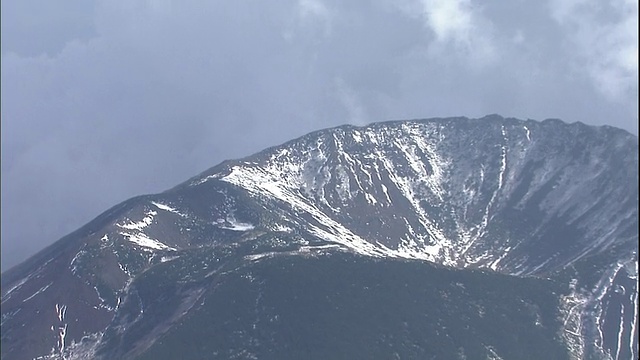 云朵在日本北海道约田山山顶的一个大坑上方漂移。视频素材