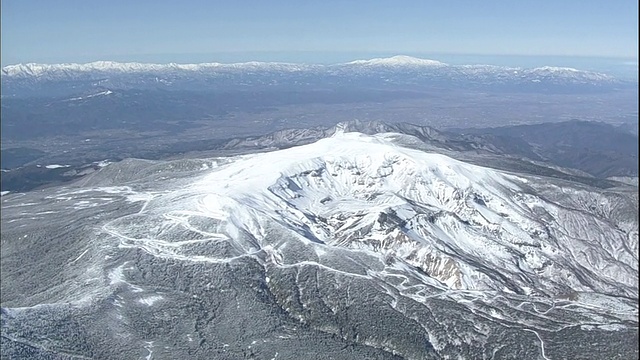 一条弯弯曲曲的道路环绕着日本藏山的一座被白雪覆盖的山脉。视频素材