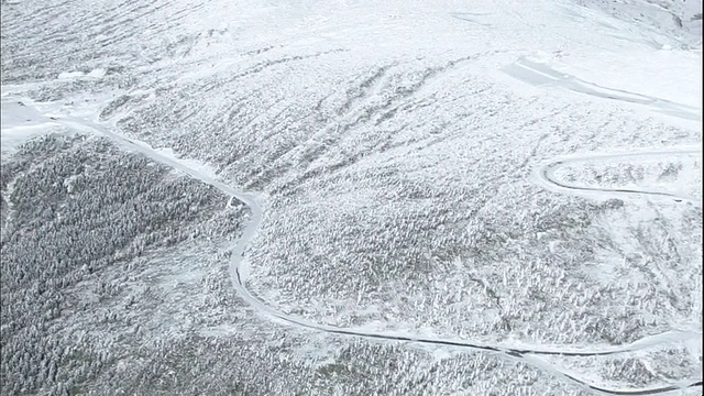 一条弯弯曲曲的道路穿过日本白雪覆盖的造山山脉。视频素材