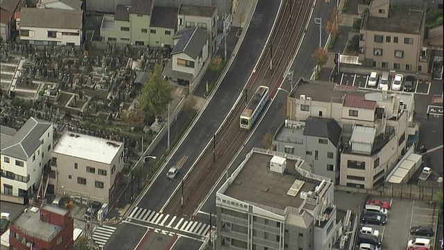 一辆Toden Arakawa线有轨电车离开乘客站台，在城市街道上行驶。视频素材