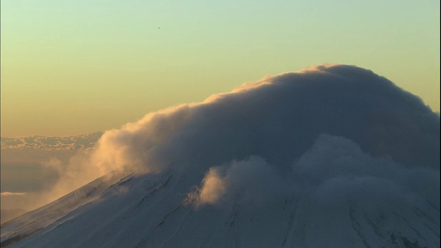 浓密的金色云雾笼罩着白雪皑皑的富士山山顶。视频素材