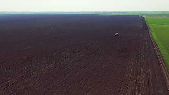 田野鸟瞰图，拖拉机在春日犁地视频素材