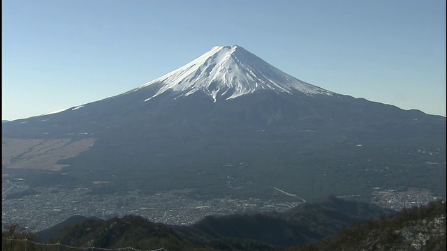 白雪皑皑的富士山在山脚下的山谷和城市投下了阴影。视频素材