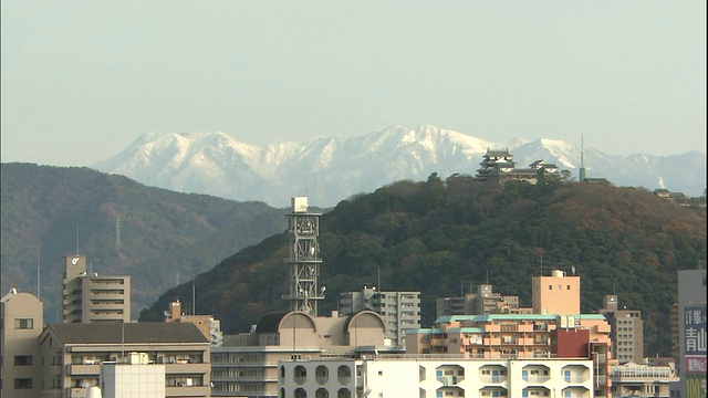 日本松山城堡(Matsuyama Castle)上耸立着石嘴山(mount Ishizuchi)。视频素材