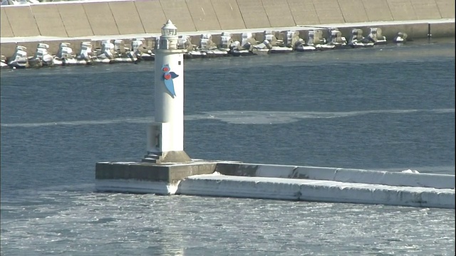 当浮冰漂浮在地平线附近时，桥桥港的灯塔被冰包围。视频素材