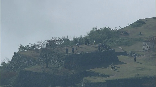 游客们仰望天空，一片云海包围着日本武田城的废墟。视频素材