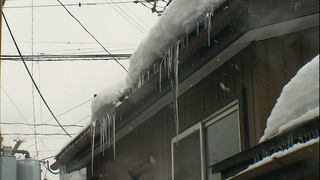 下雪时，冰柱挂在屋檐上。视频素材