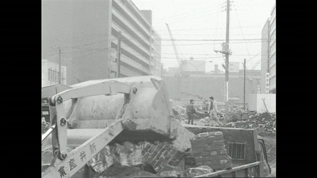 在东京西新宿区的建筑工地，一辆挖土机将碎石倒进一辆自卸卡车。视频素材