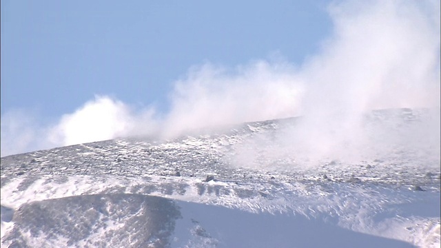 一缕白色的羽毛在日本浅山雪山顶上的蓝色天空中翻腾。视频素材