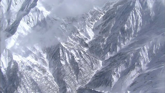 雪覆盖了谷川山陡峭的山坡，云层在深谷中漂移。视频素材