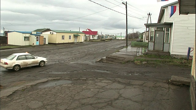 一辆汽车行驶在择日岛泥泞的道路上，俄罗斯国旗在风中飘扬。视频素材