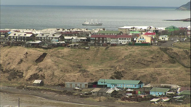 船只停泊在择日岛(Etorofu Island)海岸附近，岸边是一座座公寓。视频素材