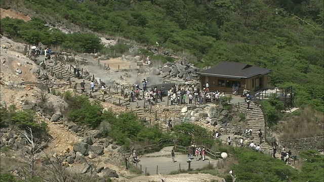 游客们在神奈川的大洼谷漫步，火山蒸汽从地面升起。视频素材