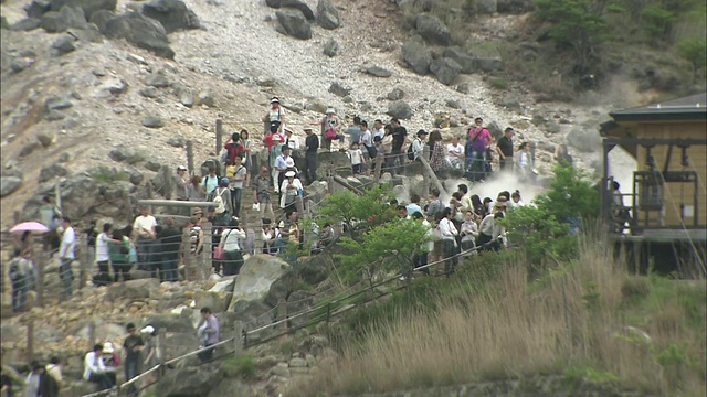 游客们在神奈川的大洼谷漫步，火山蒸汽从地面升起。视频素材