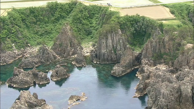 一艘游船经过崎岖的，尖峰状的岩石结构沿佐渡岛海岸，日本。视频素材