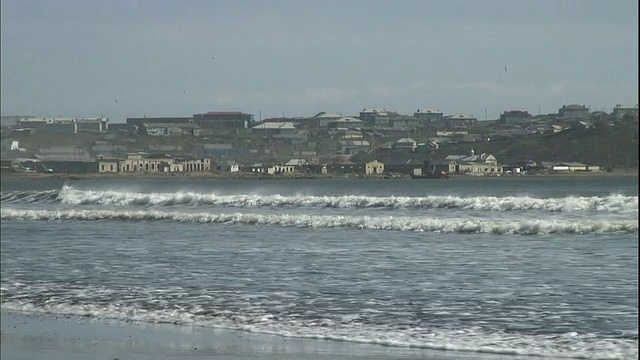 海浪拍打在国志岛附近的一个海岸村庄的海滩上。视频素材