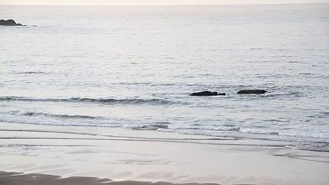 在一个阳光明媚的日子里，海浪翻滚着涌向沙滩视频素材