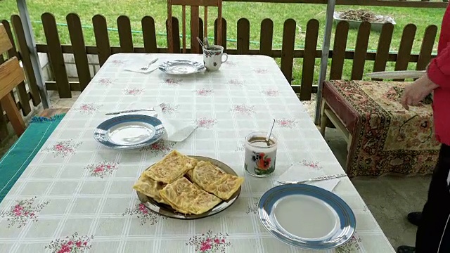 一位老年妇女在院子里为餐桌服务视频素材