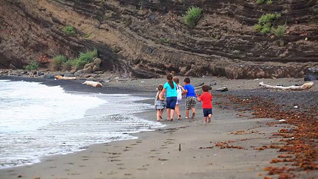 孩子们沿着冲浪线在海滩上奔跑视频素材