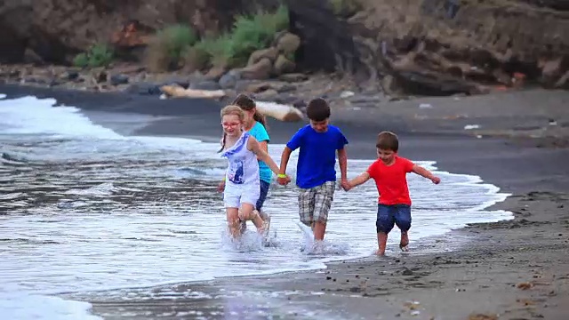 孩子们沿着冲浪线在海滩上奔跑视频素材