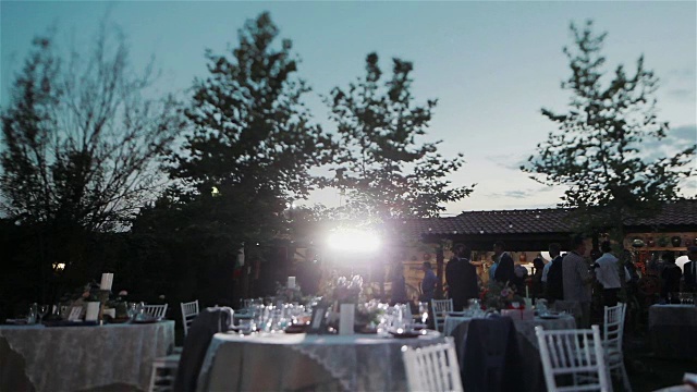 户外餐厅为周年招待会或婚礼而设的节日餐桌。专业灯光安排。在派对上工作的专业活动摄影师。焦点从桌子转移到摄影师和任务视频素材