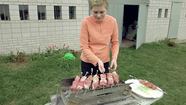 女孩把烤肉串和肉放在火盆上视频素材