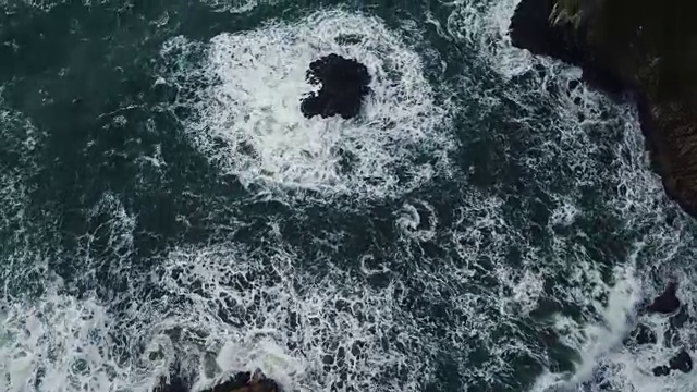 鸟瞰图的纹理海模式和岩石悬崖与海浪碰撞视频素材