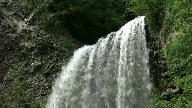 水从岩石峭壁上倾泻而下，落入池塘。视频素材