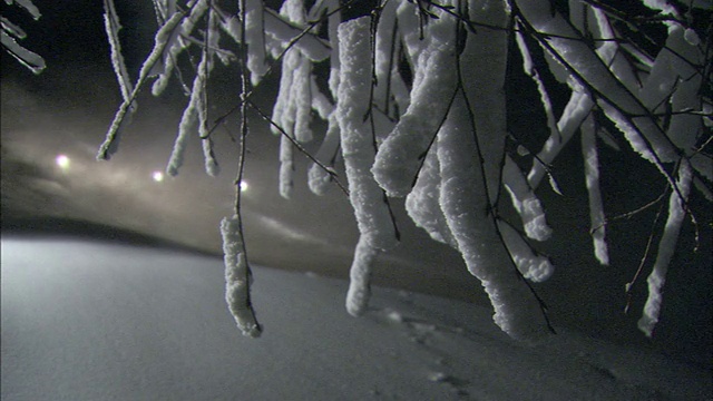 当人造雪在空中飘动时，灯光在滑雪坡顶发出光芒。视频素材