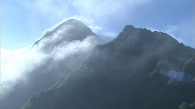 阳光透过覆盖在崎岖山峰上的炽热的雾照耀着。视频素材