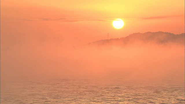 炽热的太阳把飘过内海的雾变成了橙色。视频素材