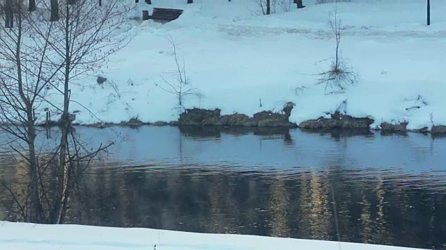 冬天的河。有光反射的河面。雪覆盖了河岸视频素材