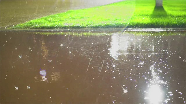 雨点溅在城市的人行道上，夏天的暴风雨，湿滑的路面状况视频素材