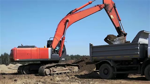 挖掘机和卡车正在装载泥土。视频素材